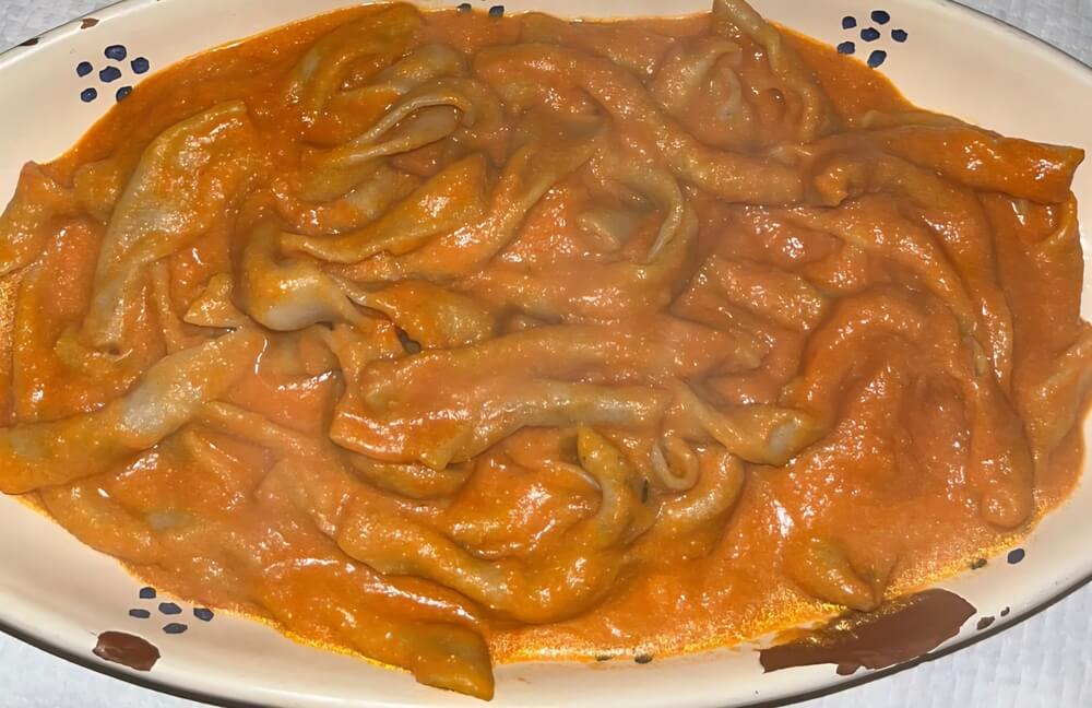 Sagne 'ncannulate con salsa di pomodoro e ricotta forte in un piatto ovale di ceramica
